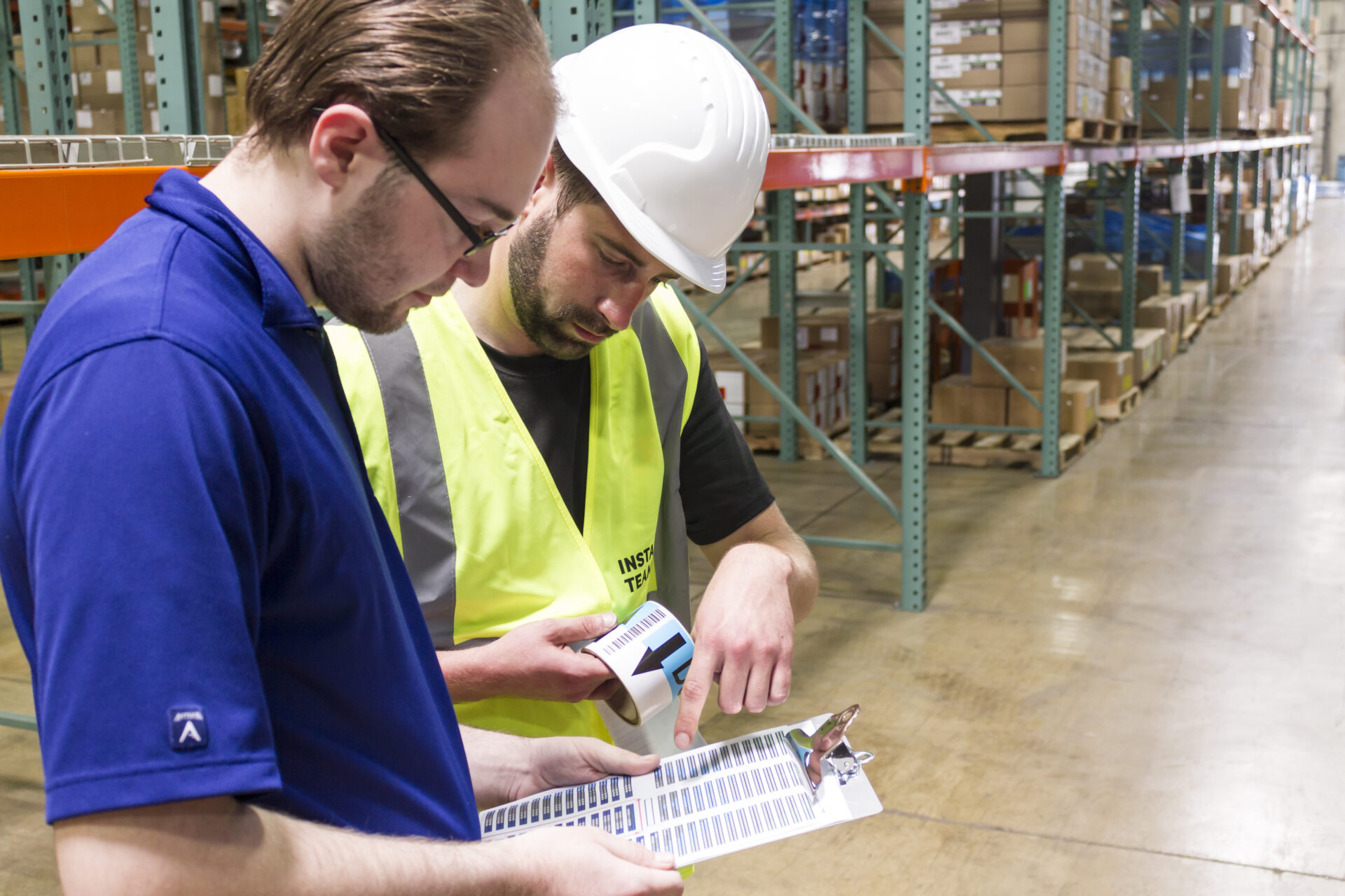 2 warehouse workers checking a label data sheet