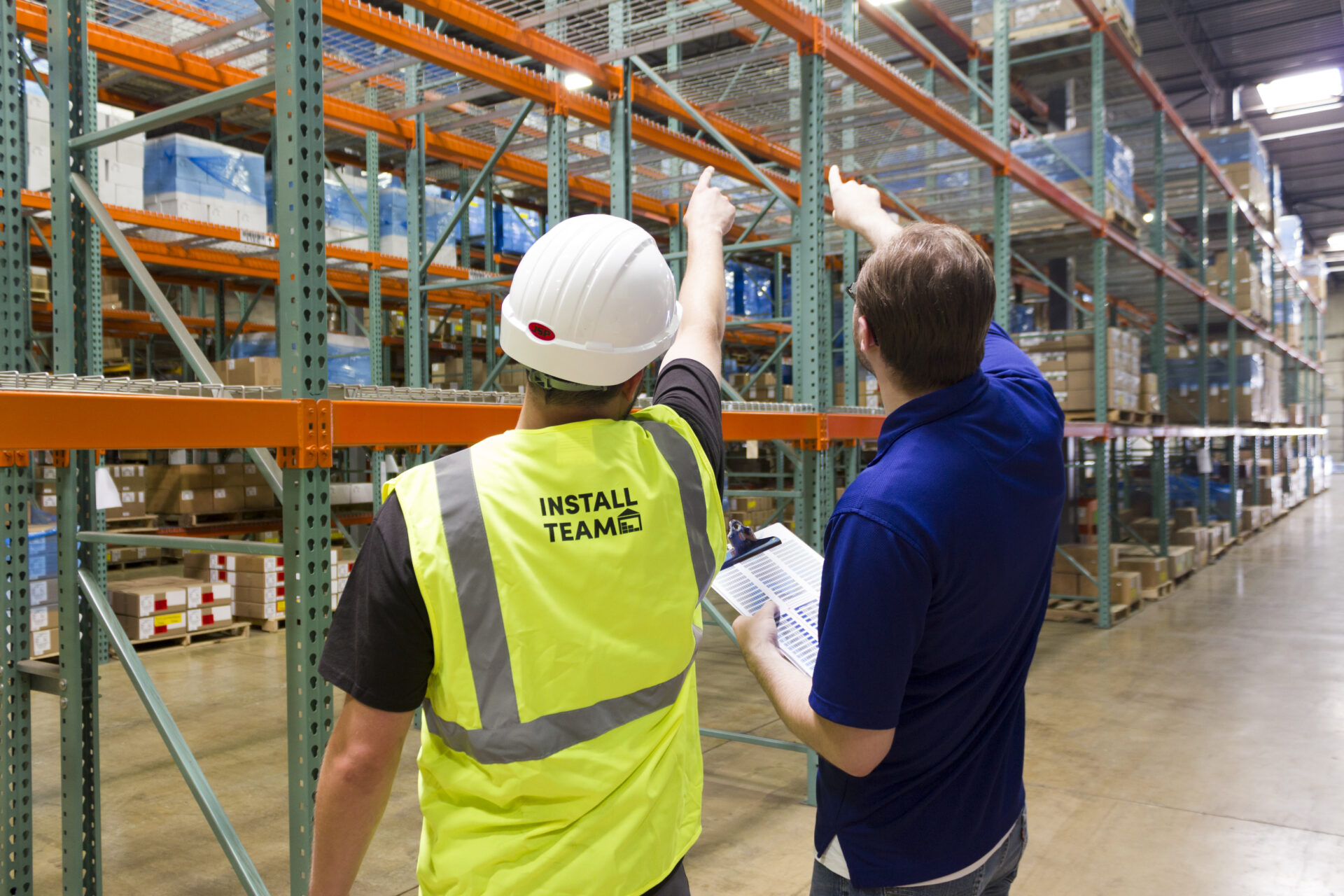 2 warehouse workers pointing at a rack