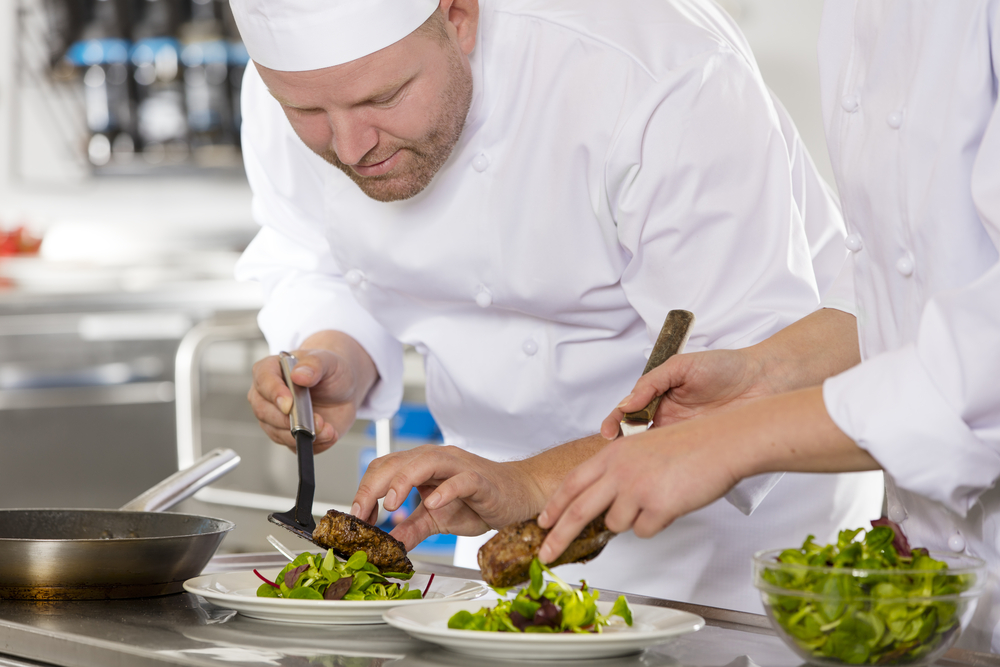 Chef plating a salad with meat